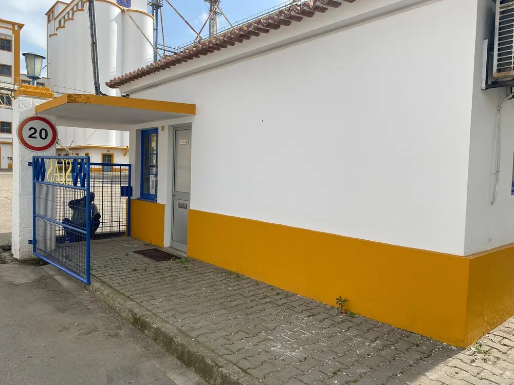 Edifício pintado de branco e amarelo com portão azul