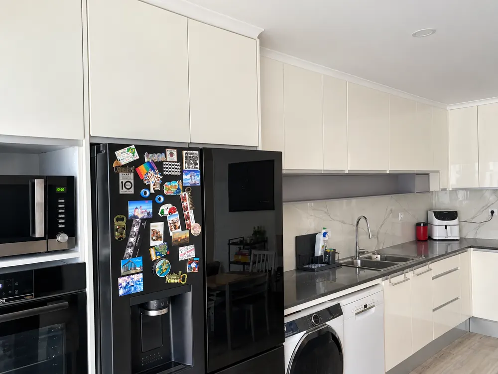 Cozinha remodelada com armários creme e frigorífico novo