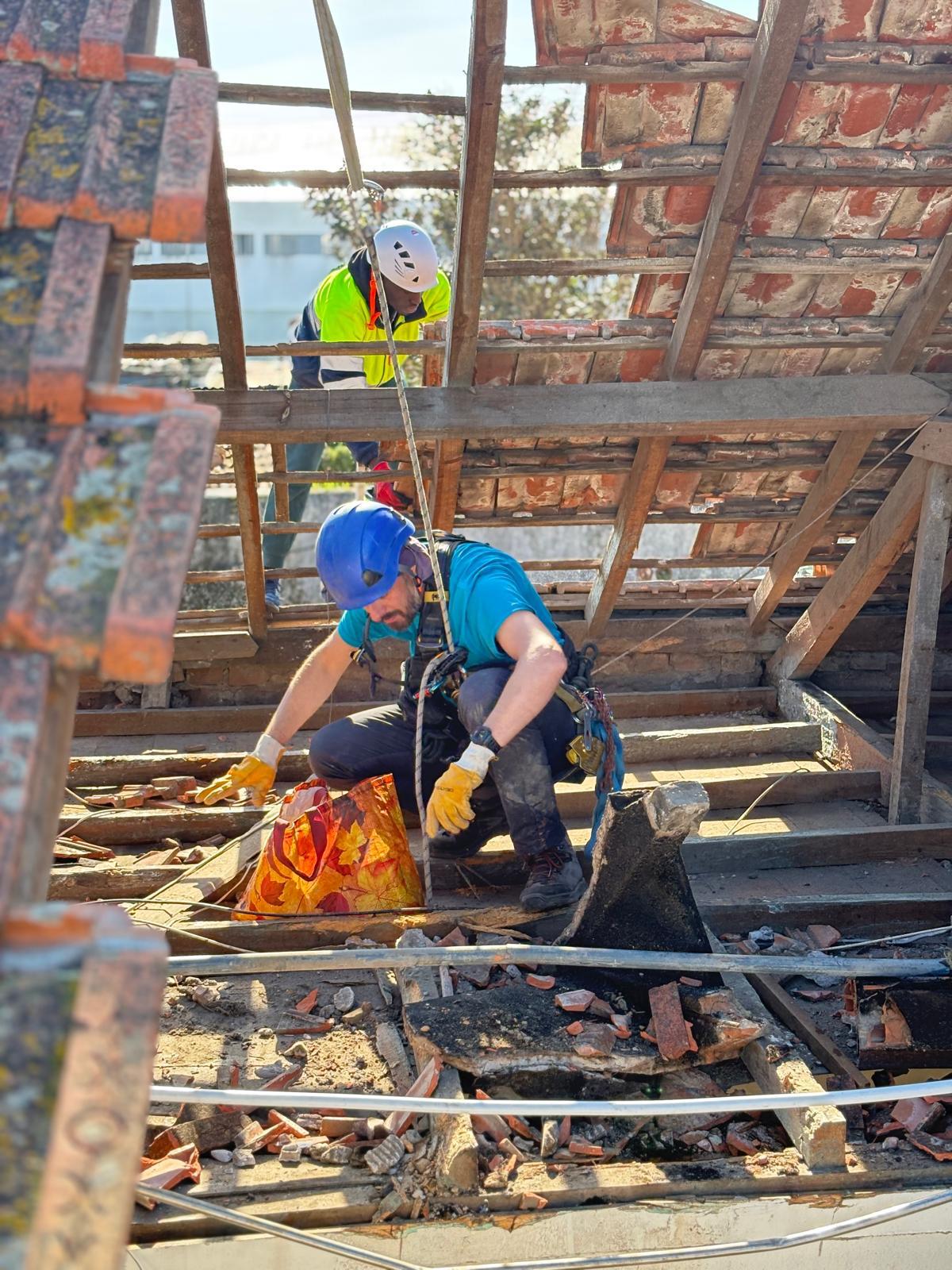 Equipa a retirar telhas antigas durante remodelação de telhado