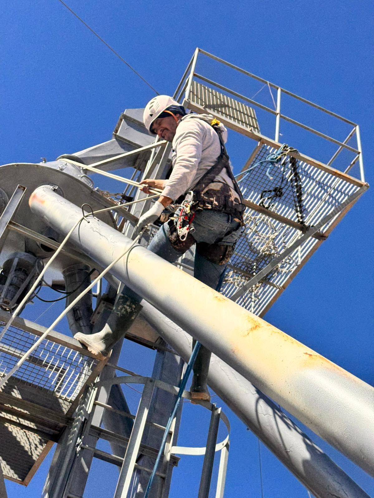 Trabalhador com arnês a descer estrutura metálica industrial